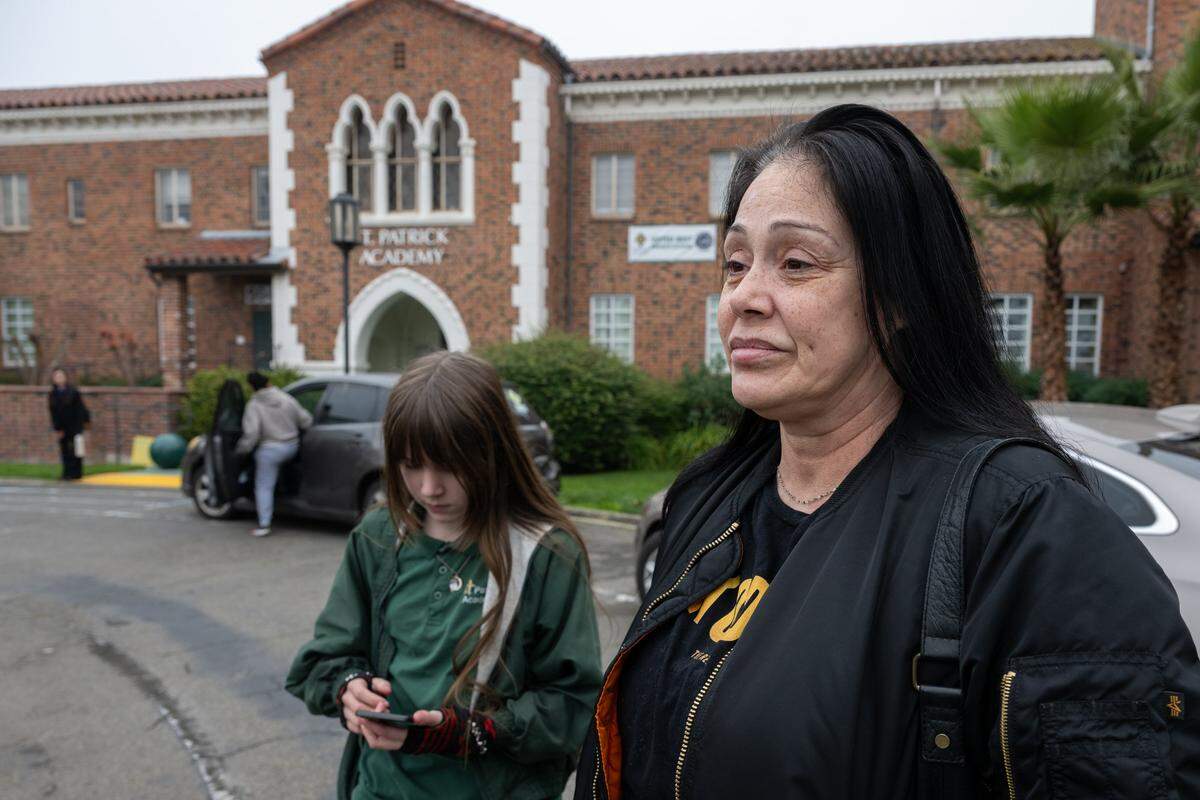 Scarlett Wallace, 11, a sixth-grader, stands with her mother, Georgia Wallace, on Friday after learning she will have to transfer to another school following the closure of St. Patrick Academy in Sacramento. Five of Georgia’s children have attended the Catholic school on Franklin Boulevard, which the diocese announced will close at the end of the school year.
