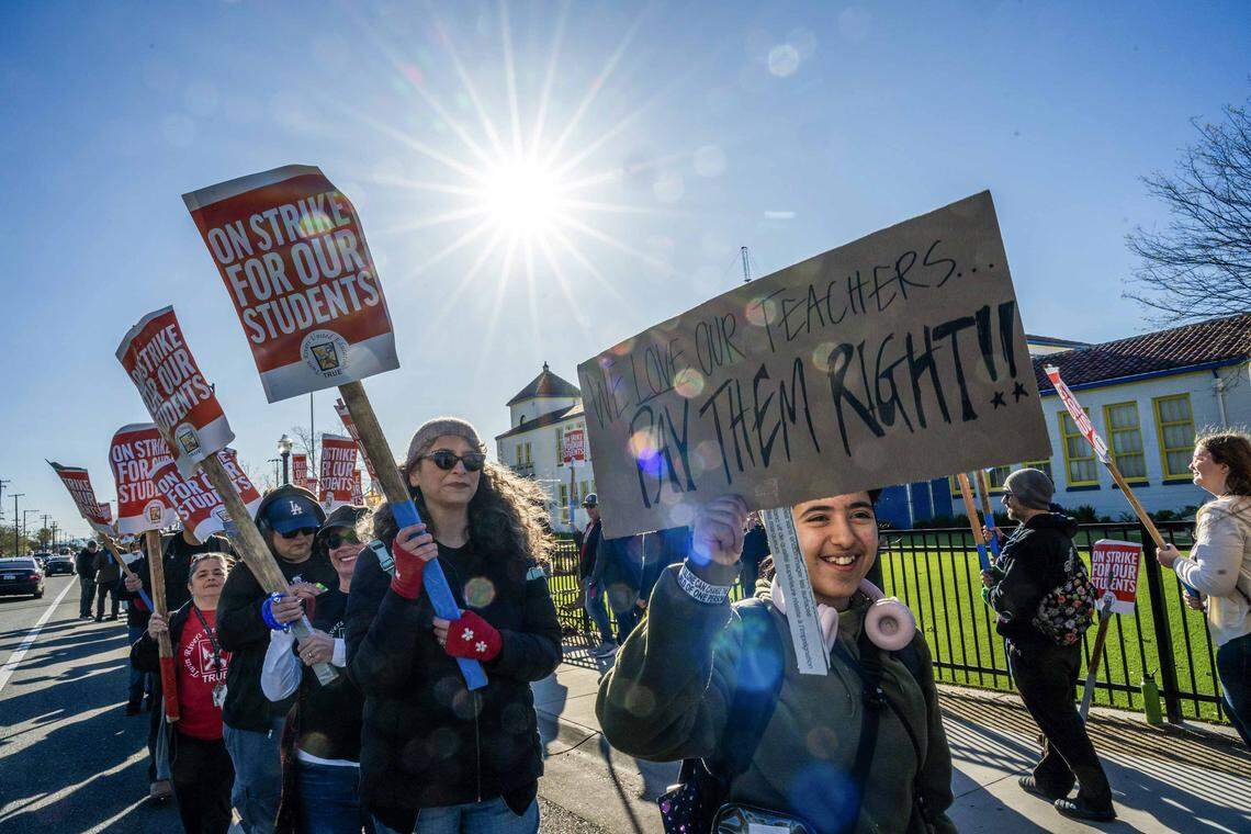 Grant High School student Oliver Gaara, right, holds a handmade sign as he participates in a strike by Twin Rivers Unified School District teachers in front of his school in Sacramento on Thursday.