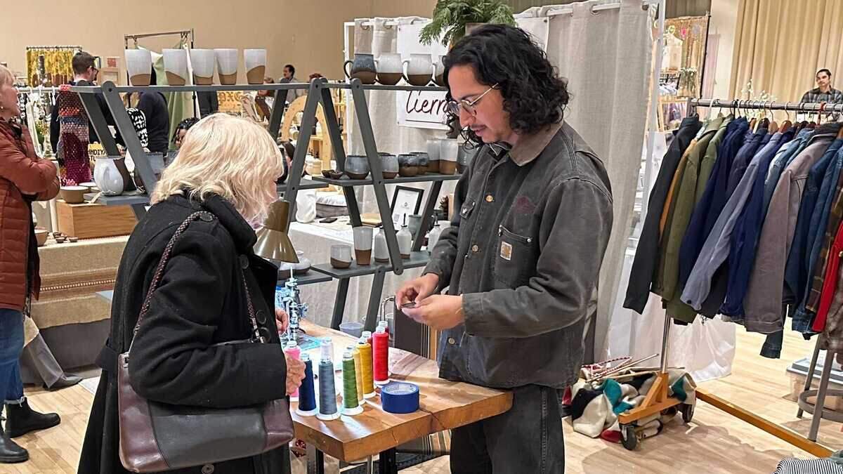 Bryan Ocegueda of Friend of Yours, a chain-stitch embroidery outfit in Fresno, talks with a shopper at the Makers Mart holiday craft fair on Saturday, Dec. 9, 2023.