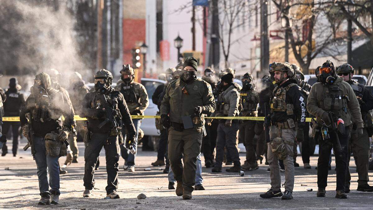 Federal agents stand near police tape as demonstrators gather near the site of where state and local authorities say a man was shot by federal agents earlier in the morning in Minneapolis, Minnesota, on Saturday, Jan. 24, 2026.