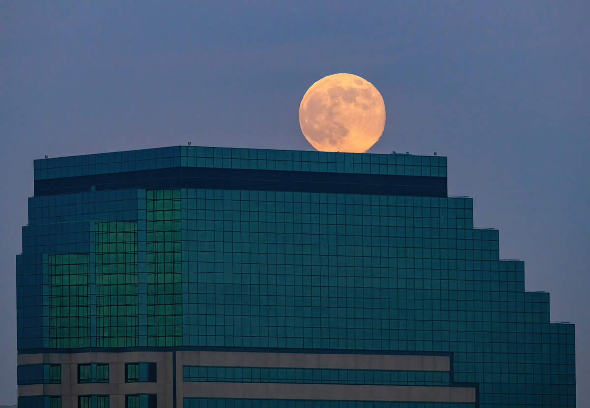 A supermoon climbs over the Emerald Tower in downtown Sacramento at dusk on Thursday. It’s the last full moon of the year.