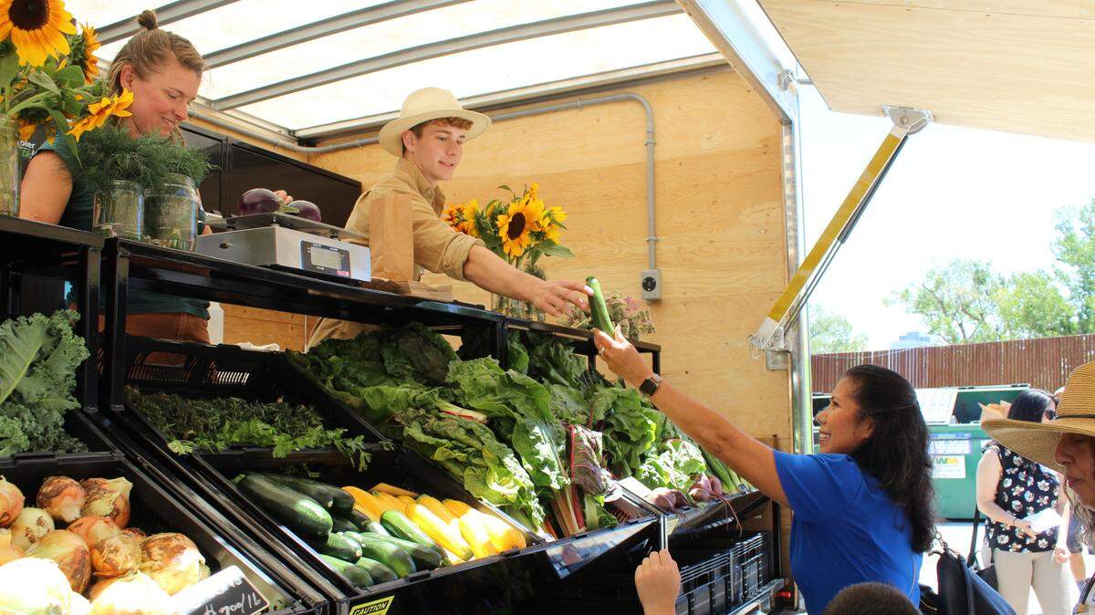 Kyle Moeller, an intern part of the West Sacramento Urban Farm Program, interacts with Mayor Martha Guerrero at the Mobile Farmers’ Market during the June 24 launch at Drake’s: The Barn in West Sacramento. Coordinator Heather Lyon, left, looks on.