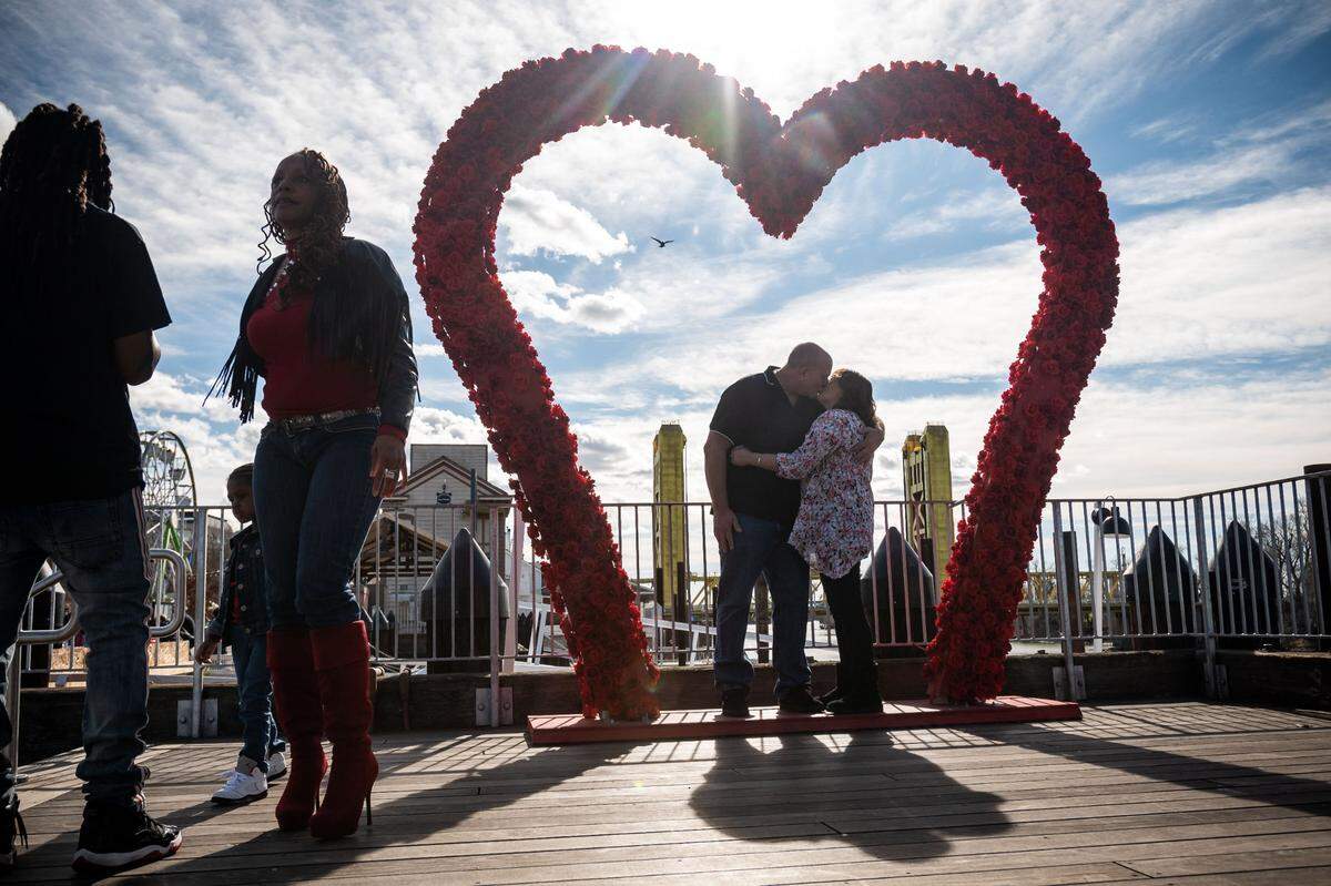 John and Marianne Dayton of Elk Grove kiss under a new Valentine’s Day-themed art piece Saturday, Feb. 13, 2021, at the Embarcadero at the Old Sacramento Waterfront. “He’s a truck driver, so he’s only home one-and-a-half days during the week.” Marianne said, “Every weekend we try to get out, do something.” Local artist Alyse Porzio of Steadfast Craft decorated the temporary 10-foot piece “Heart Arch” with hundreds of flowers for people to surround people.