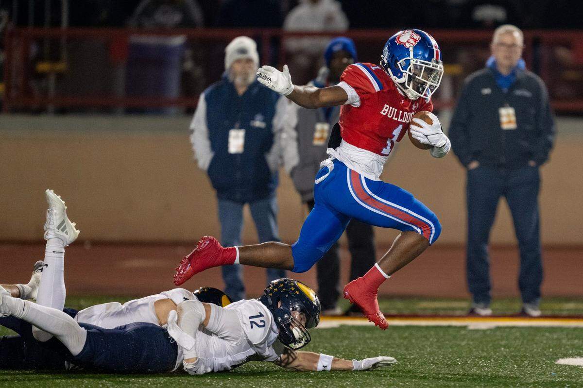 The Folsom Bulldogs’ Carter Jackson (1) leaps over the Oak Ridge Trojans’ Justen Womack (12) in the first half of the 2024 CIF Sac-Joaquin Section l Football Championship on Saturday, Nov. 30, 2024 in Sacramento.