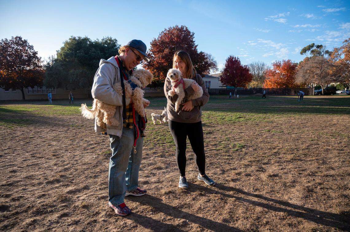 Land Park residents Mark and Leann Holtsman hold their dogs Benji and Cocco on Friday at Sierra 2 Park. The couple visits the park with their pets two or three times a week, and Leann said the unofficial dog park has formed its own little community. “It’s usually the same people that come out,” she said. “Everybody kind of knows everybody.”