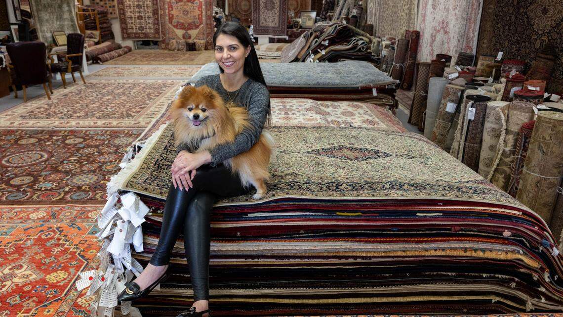 Rebecca Yaghoubian sits among thousands of carpets with her dog, Teddy, at Mansour’s Oriental Rug Gallery in Sacramento on Tuesday, April 28, 2026. The family-owned business is closing its Fair Oaks Boulevard location after nearly 50 years, while maintaining a second store in Roseville.