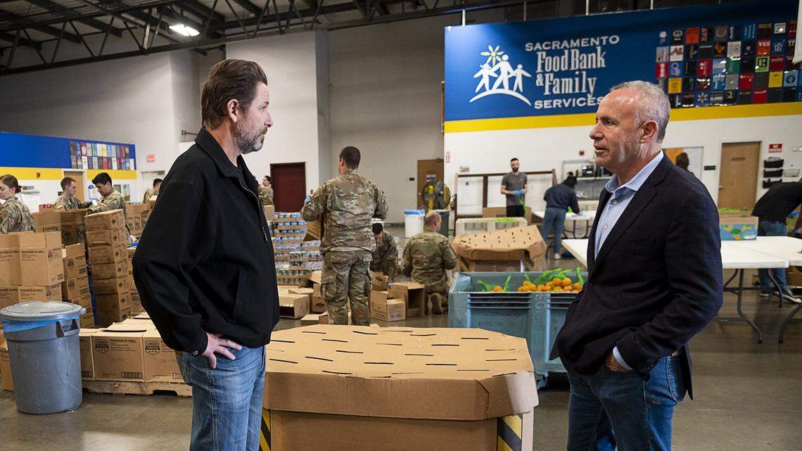 Sacramento Mayor Darrell Steinberg, right, talks with Sacramento Food Bank CEO Blake Young in March 2020, as the food bank announced that 1,380 families would receive two bags of groceries per week. The nonprofit pulled back on some extra services during the pandemic.