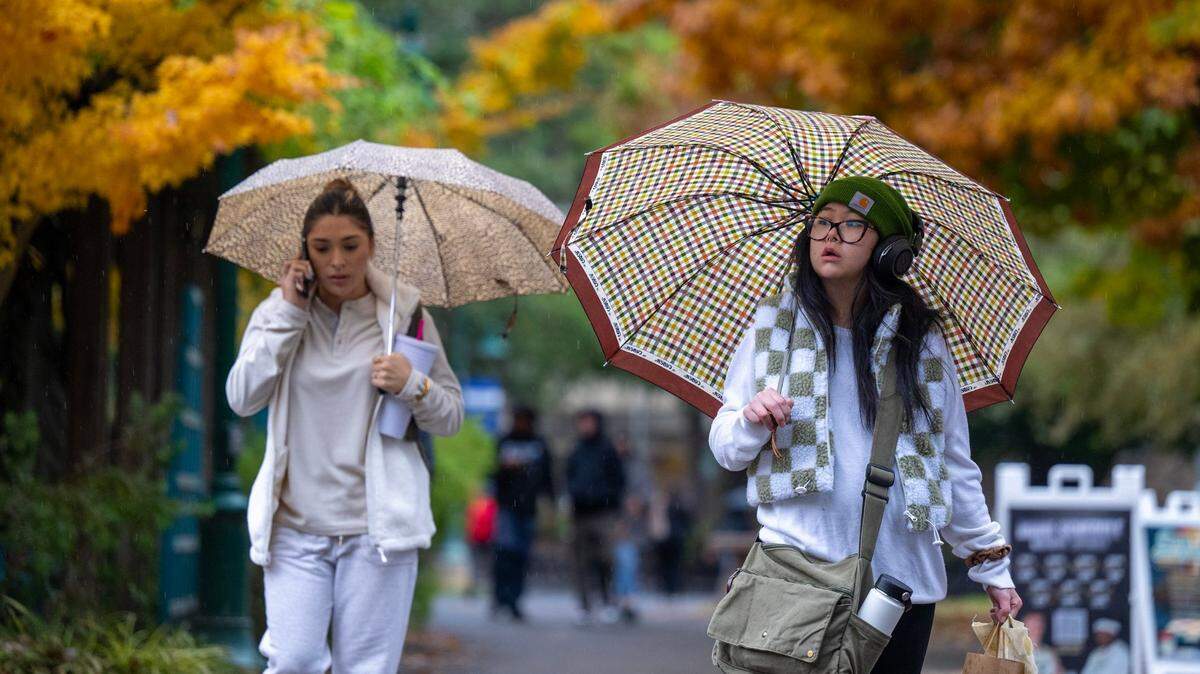 Sacramento State student Jessica Fong, right, walks through the rain on the campus on Nov. 21, 2024. Golden 1 Credit Union will invest $1 million in student well-being at Sacramento State over the next four years, officials announced Monday. 