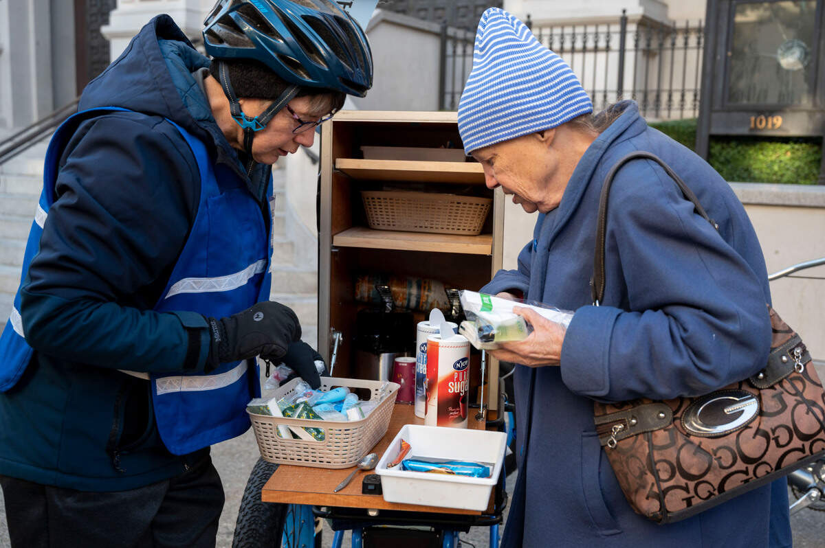 Sister Libby Fernandez with Mercy Pedalers helps a woman named Paula get needed items while giving out coffee and other supplies in front of the Cathedral of the Blessed Sacrament earlier this month.
