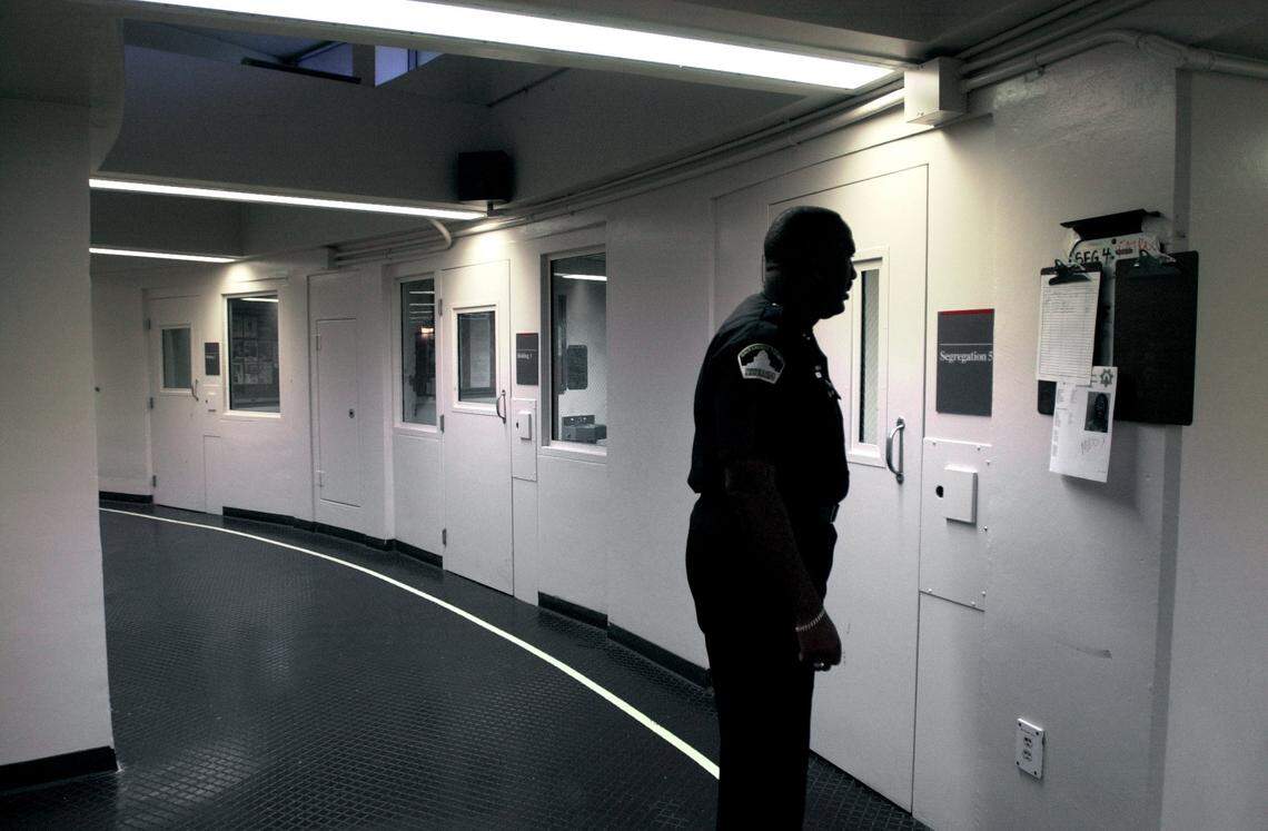 Then-Capt. Jim Cooper, jail commander, checks the roster along a row of segregation cells in the Main Jail’s booking area in 2002.