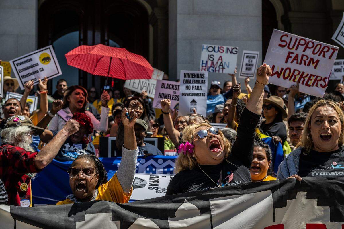 Della Currie, left, and Juliet Castro, right, raise their fists as they join hundreds of demonstrators at the state Capitol in Sacramento on Monday to show their support for two legislative proposals to address the cost of housing in California. On of the proposals, Senate Bill 567, would lower the maximum allowable rent increase to 5% and prevent landlords from evicting tenants without a legal reason.