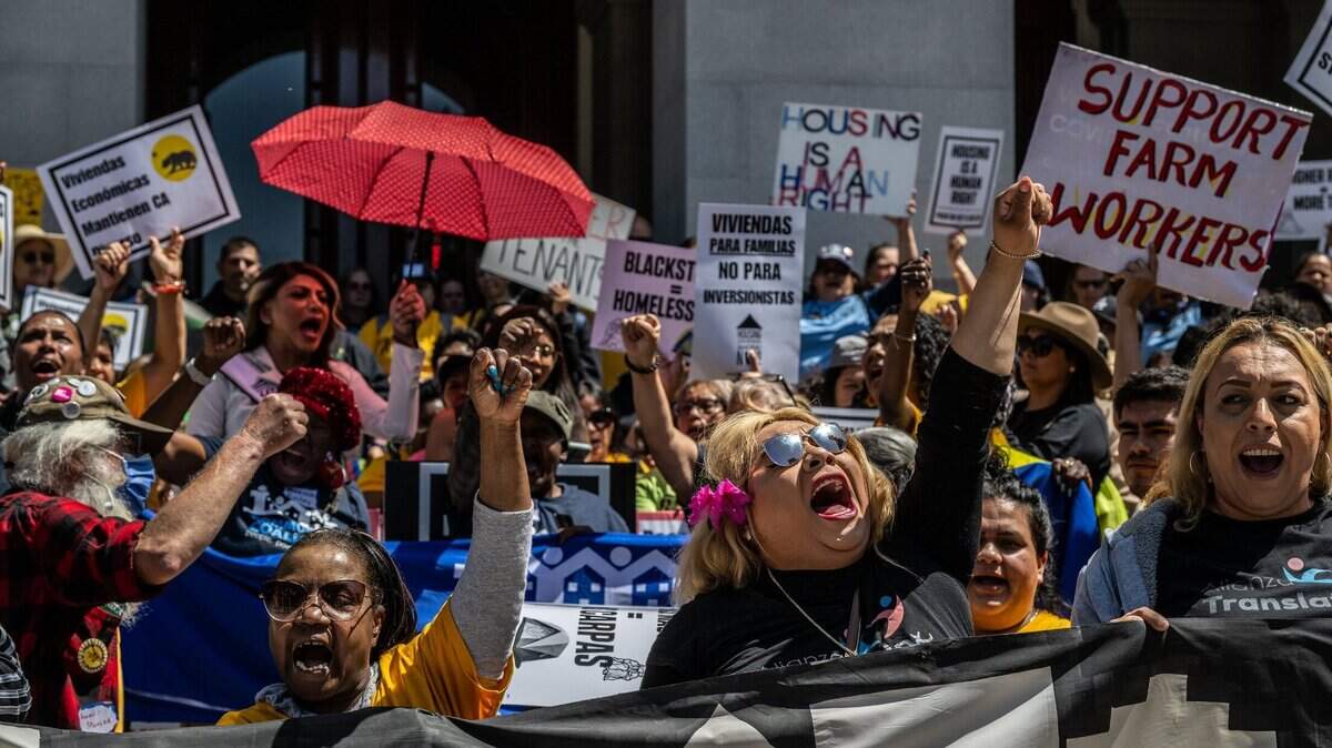 Della Currie, left, and Juliet Castro, right, raise their fists as they join hundreds of demonstrators at the state Capitol in Sacramento on Monday, April 24, 2023, to show their support for two legislative proposals to address the cost of housing in California. Proposition 33 would strengthen renter protections.
