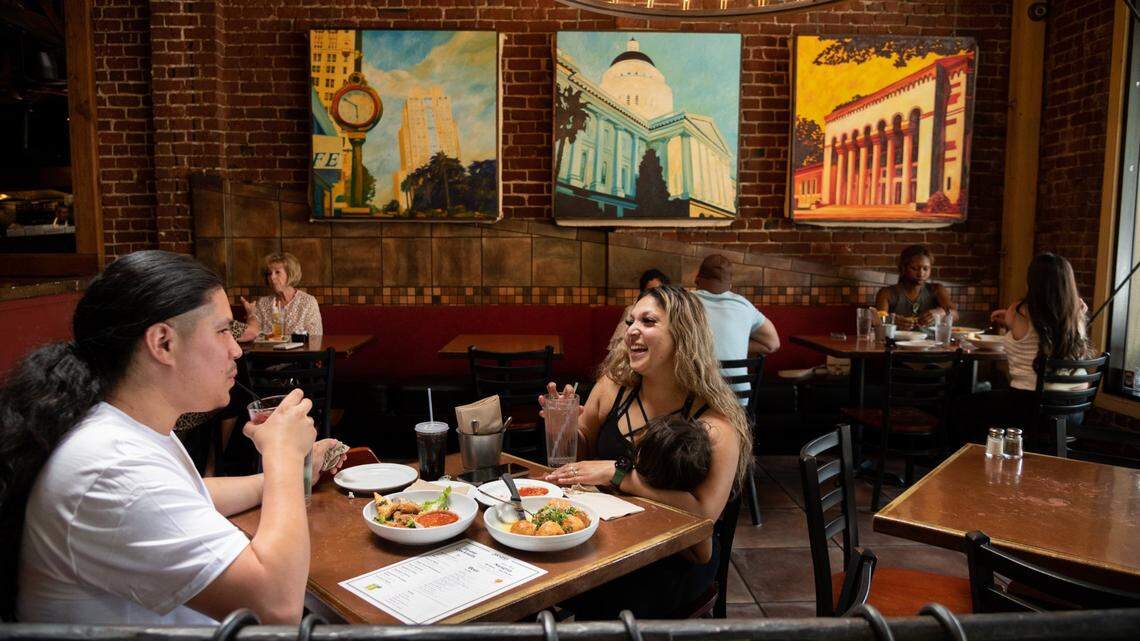 Efren and Myesha Garcia share some appetizers during happy hour at Paesanos in Sacramento on Friday, June 10, 2022, as Myesha holds their son Josiah, 2.