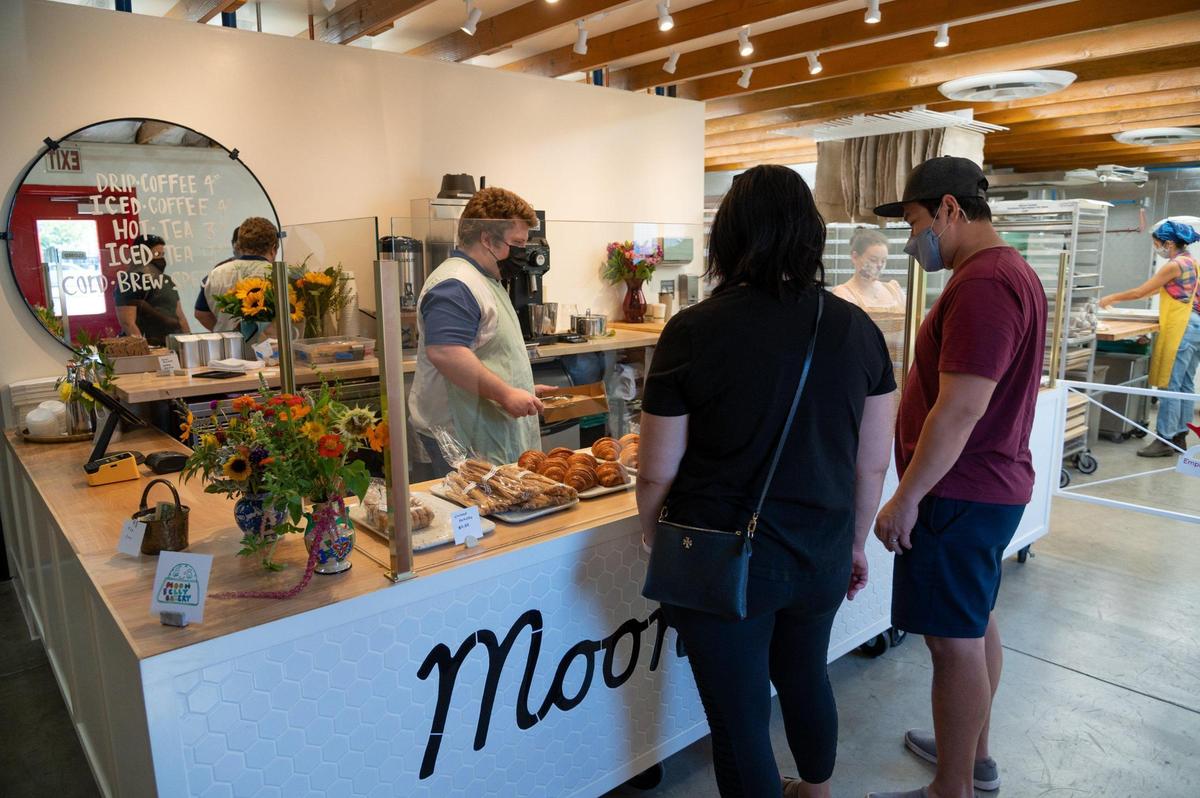 Customers look at the display case and select pastries during opening day at Moonbelly Bakery in Sacramento on Friday, Aug. 19, 2022.