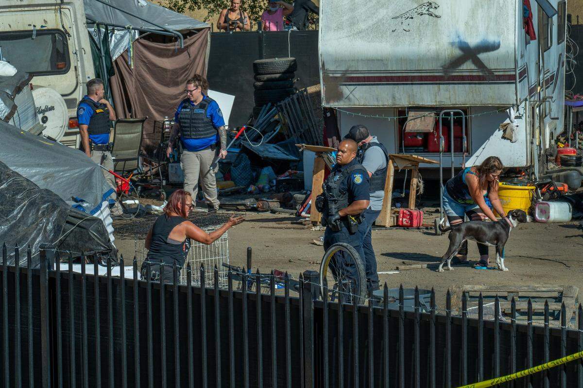 Chastity May, 50, left, tries to save her trailer, belongings and three dogs as Sacramento police and city crews dismantle Camp Resolution on Monday. “I had to fight with them to get another bag of clothes,” said May, who had lived at the homeless encampment for two years. Her trailer was towed, and the tent she received from nonprofit Hope Cooperative was tagged by park rangers with a note to move on Wednesday.