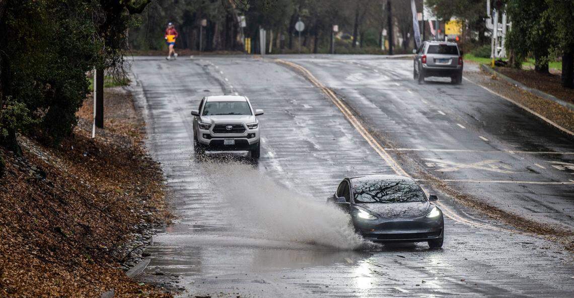 A Tesla crosses a flooded section of Sutterville Road in Sacramento on Tuesday, Dec. 27, 2022 as rain fell in the Sacramento region.