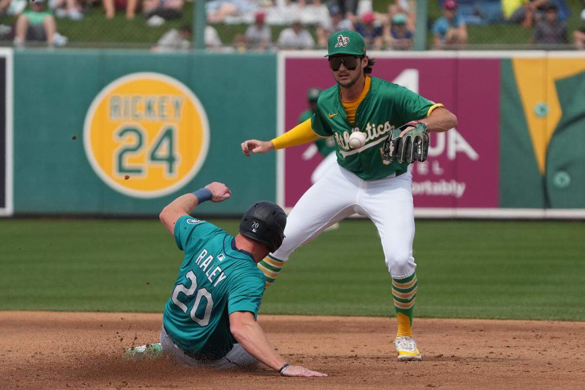 Mar 17, 2025; Mesa, Arizona, USA; Oakland Athletics shortstop Jacob Wilson (5) avoids Seattle Mariners outfielder Luke Raley (20) in the second inning at Hohokam Stadium. Mandatory Credit: Rick Scuteri-Imagn Images
