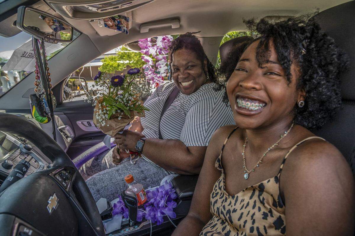 Danielle Mais is all smiles after going through Sacramento Charter High School’s drive up graduation celebration with her mom, Kerene Tucker-Mais, left, and getting her graduation cap and gown, flowers and a lawn sign poster with her senior picture on it, Wednesday, May 27, 2020.