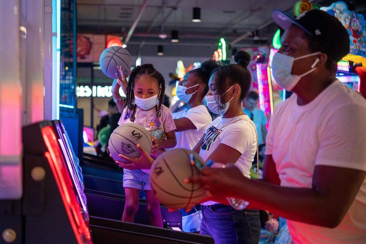 Rick Brumfield, far right, and his wife, Neenee Brumfield, shoot hoops at a basketball attraction with their children, 4-year-old Zy and 16-year-old Moni, all of Sacramento on opening day at Round1 Bowling & Amusement at Westfield Galleria at Roseville on Saturday.