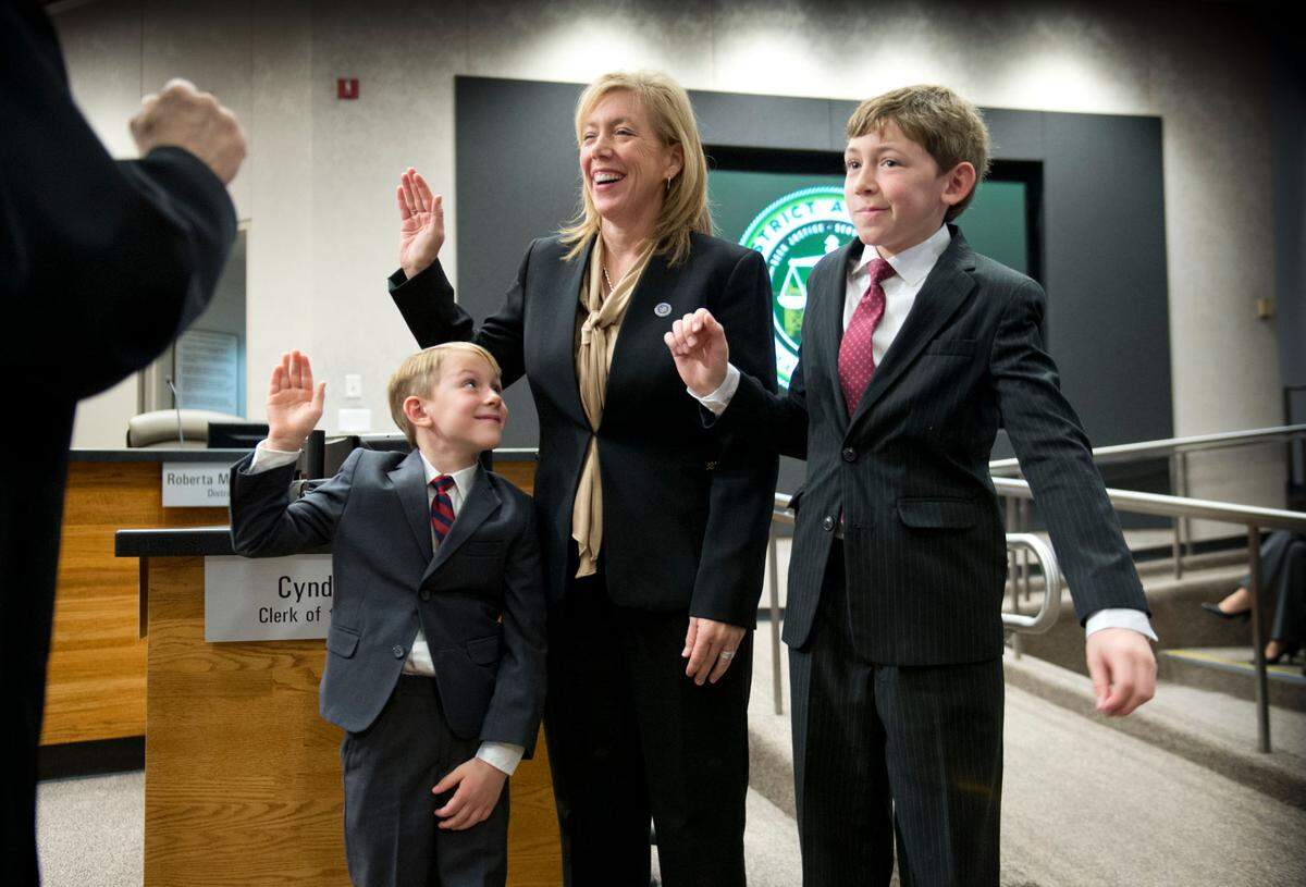 Anne Marie Schubert is sworn in by Judge Laurie Earl as the Sacramento County District Attorney as her sons Jacob, 6, and Riley, 11, join her at the Board of Supervisors chambers, in January 2015.