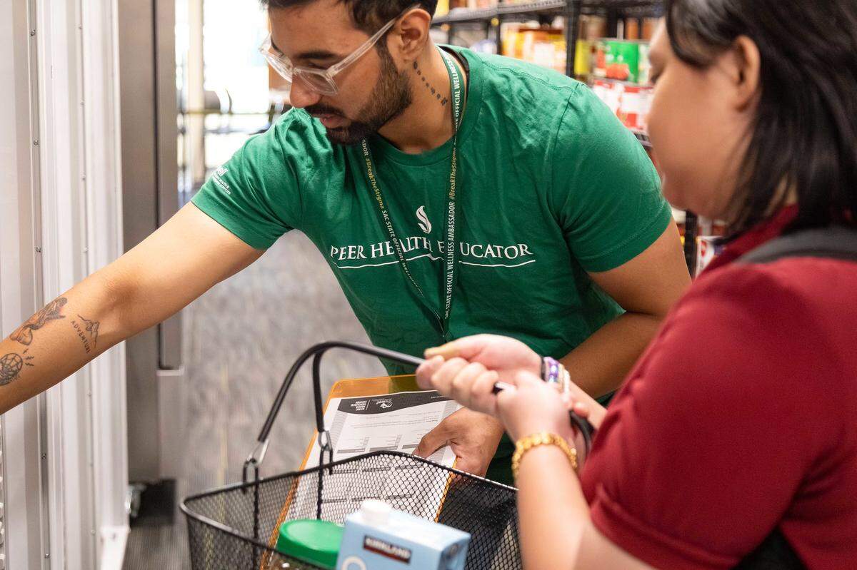 Student assistant Naman Gusain, left, plays the role of the personal shopper, and Faith Ballesteros learns how it feels to be a client in a training exercise at Sacramento State’s basic needs resource center.