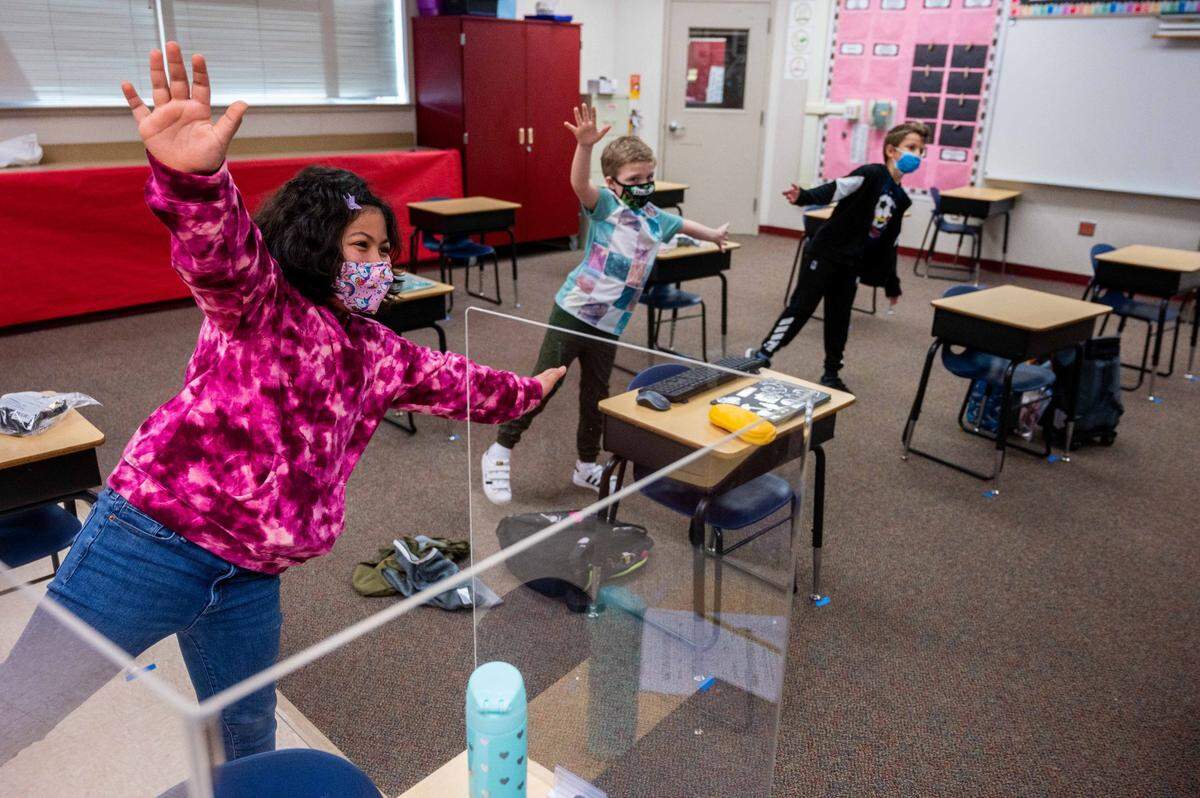 Third graders Gabi Wade, left, Gavin Ruggles and Alex Pop, right, take a movement break during class at Two Rivers Elementary School in Sacramento on Monday, March 8, 2021, the first day that the students at the Natomas Unified school attended in person instruction this year because of the coronavirus pandemic. Only three students were in the classroom.