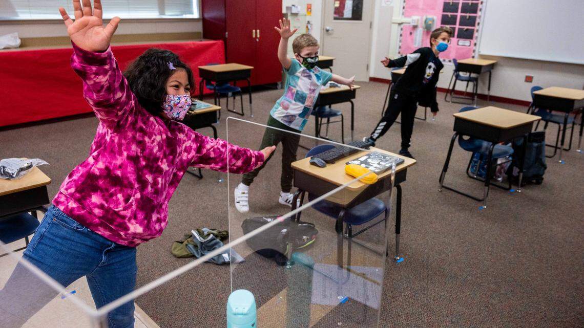Third graders Gabi Wade, left, Gavin Ruggles and Alex Pop, right, take a movement break during class at Two Rivers Elementary School in Sacramento on Monday, March 8, 2021, the first day that the students at the Natomas Unified school attended in person instruction this year because of the coronavirus pandemic. Only three students were in the classroom.