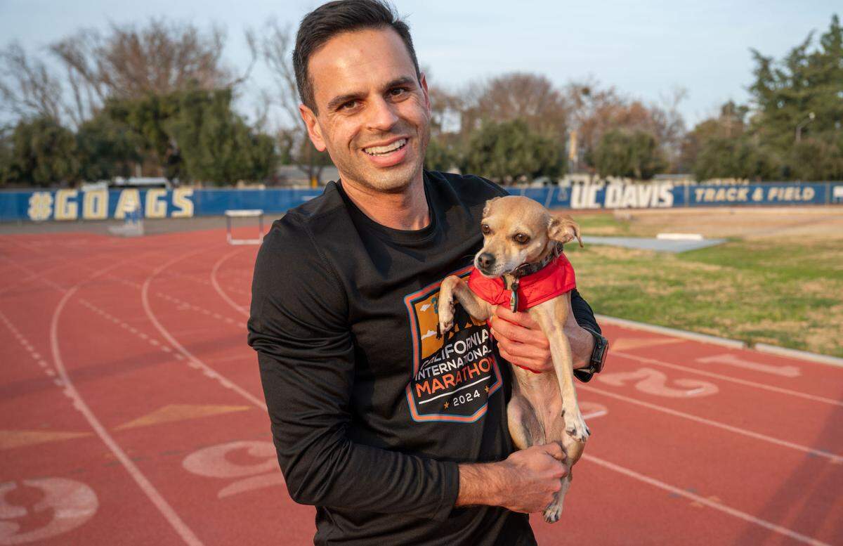Andrew Owens holds his running partner Jellybean earlier this month at the track at UC Davis where they train every week.