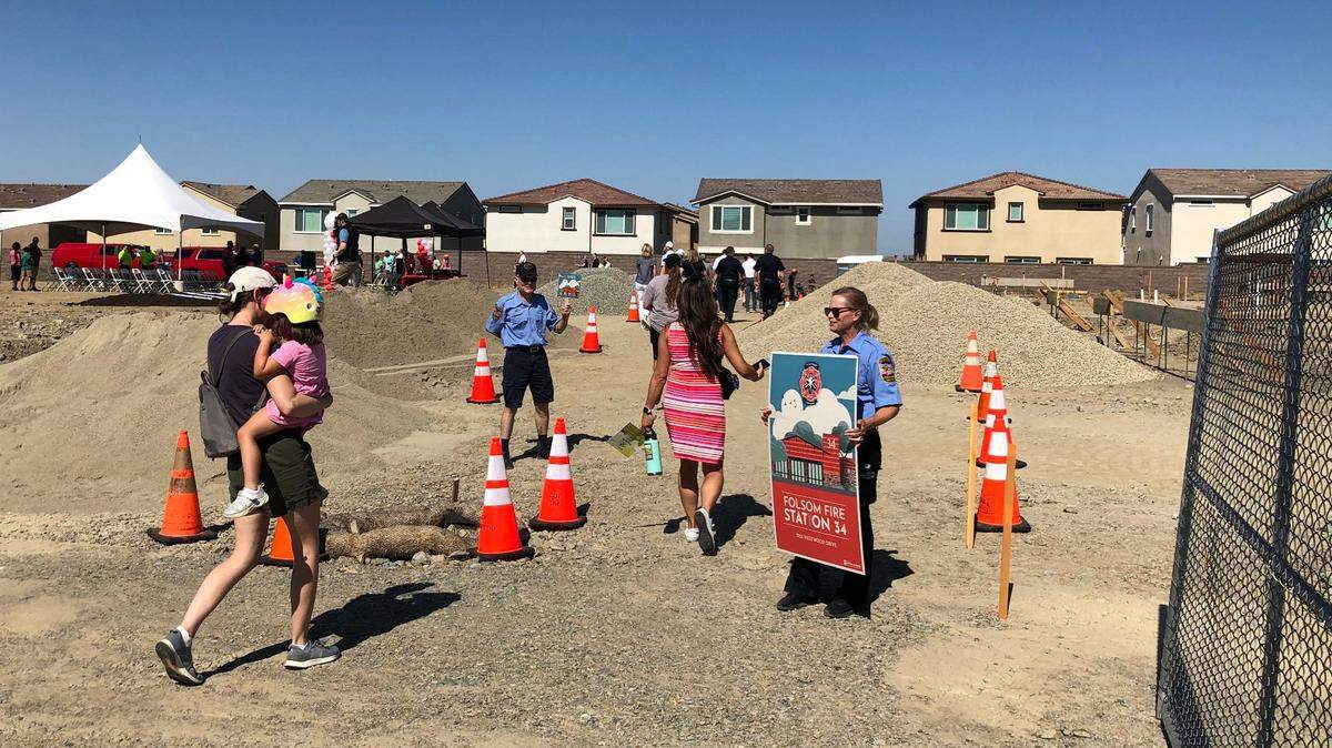 Norton Eastment, left, and Gayle Silvey, Citizens Assisting Public Safety volunteers within the city of Folsom, hold signs advertising the new Station 34 that broke ground as citizens finish a community walk Thursday, June 29, 2023. The ceremony was part of an additional groundbreaking and community walk earlier that morning from Prospector Park, one of nine planned parks in the Folsom Ranch Developments south of Highway 50.