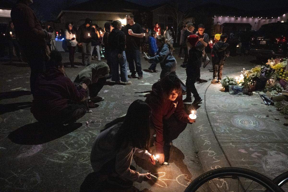 Neighbors light candles and draw with chalk during a vigil on Mill Water Circle in Rancho Cordova on Sunday, Feb. 1, 2026, to remember the Vallerga family who were found dead in their home on the street on Jan. 27 in an apparent murder-suicide.