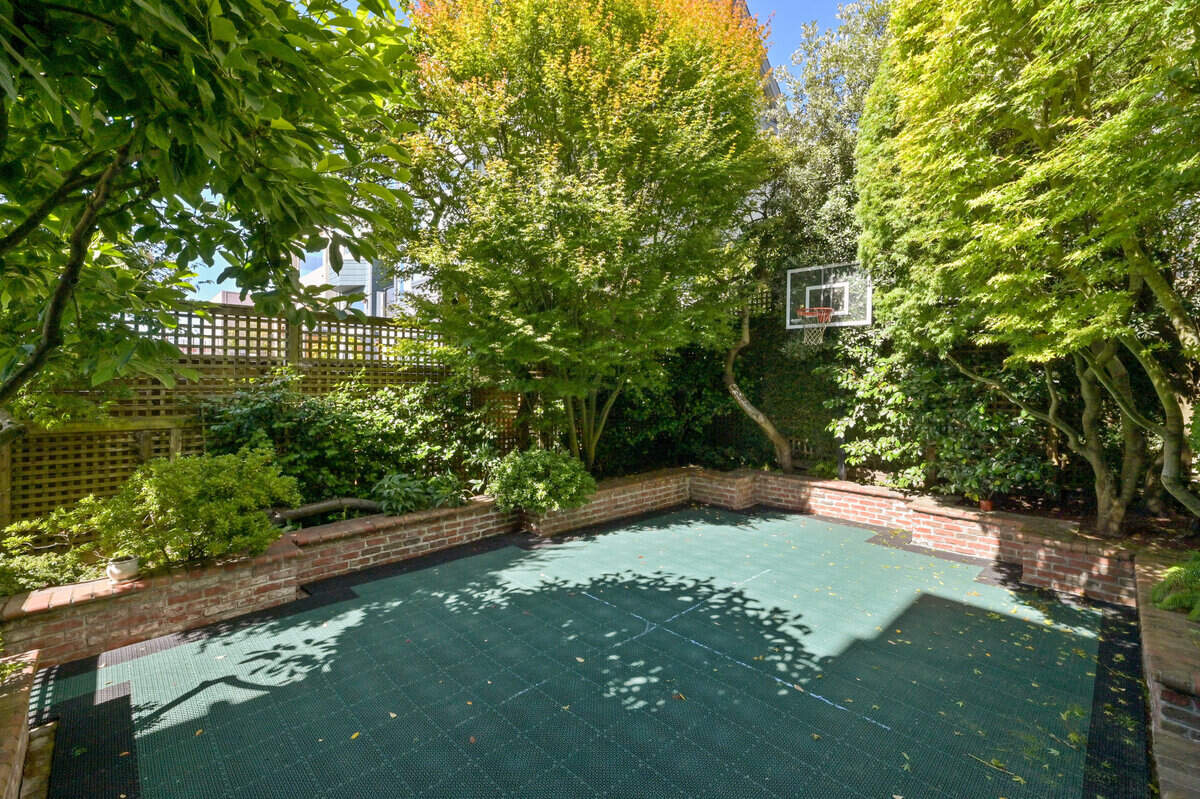 The basketball court is located in a shady garden area.