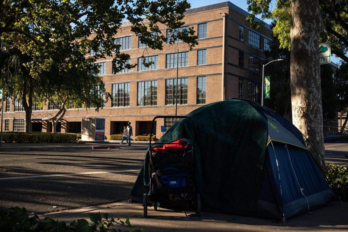Jasmine Belarmino and her boyfriend, John, have been waiting to secure housing for about a year while sleeping in a tent, seen across the street from a five-story building at Third and R streets that is owned by the California Public Employees’ Retirement System and sits vacant Saturday, Aug. 20, 2022, in downtown Sacramento. The city and Sacramento County had eyed the building as a site for a homeless shelter.