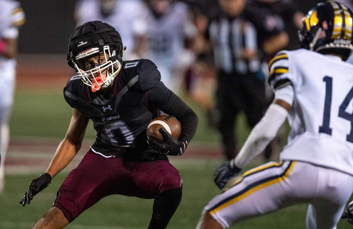 The Woodcreek Timberwolves' Trace Murchison (0) looks to evade Inderkum Tigers’ Jayden Corry (14) as he picks up first down yardage on a reception in the fourth quarter on Friday in Roseville. 