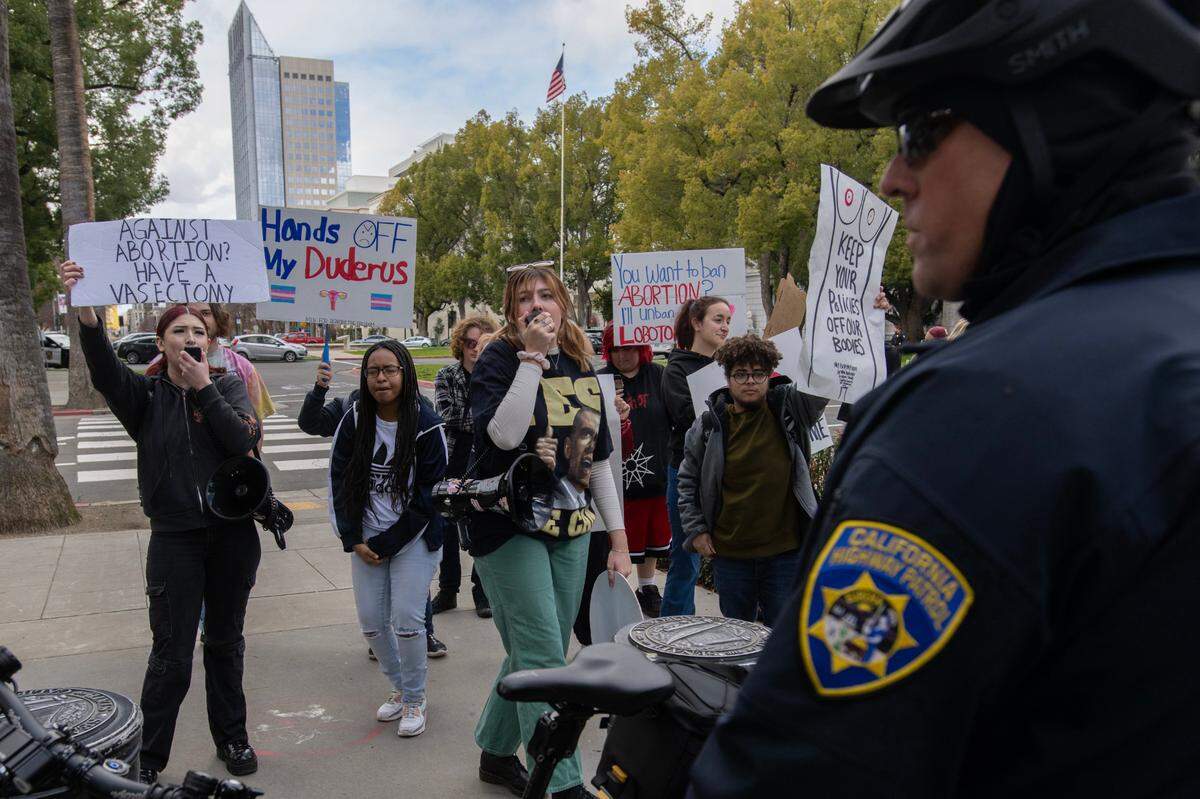 Abortion-rights supporter Larkin Dewyer, center with megaphone, yells at abortion opponents during the 2023 California March For Life at the state Capitol in Sacramento on Monday, March 6, 2023.