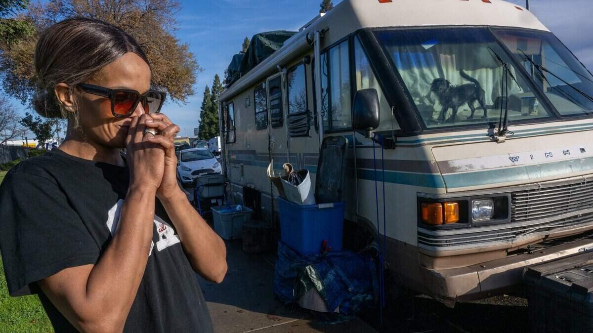 Nicole Casper, de 42 años, se muestra preocupa por que la desalojen, mientras su perro la mira desde la ventana en la calle Opportunity, en el norte de Sacramento, el jueves. "Es estresante no saber si van a venir", dijo Casper.