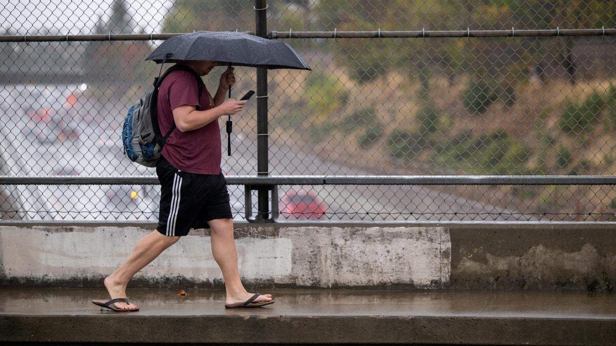 A pedestrian walks in the rain on 48th Street over Highway 50 in Sacramento on Tuesday, Nov. 1, 2022.