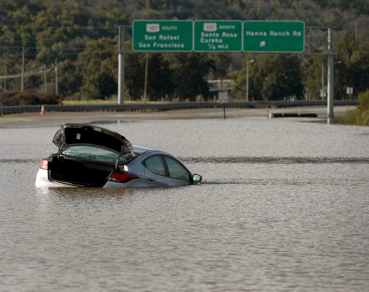 Floodwater surrounds a car stranded on Highway 37 near Novato after storms in January 2017. Flooding from levee failures and high tides has repeatedly shut down Highway 37, but Caltrans' $500 million interim project does not include measures to protect against similar future events.