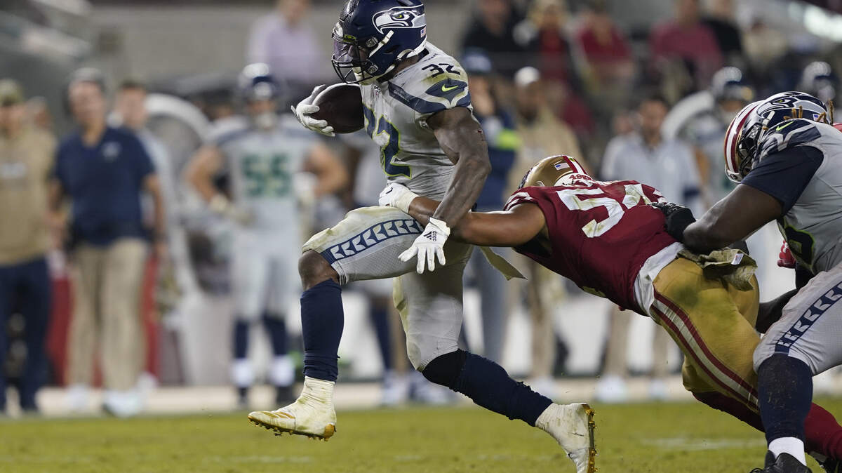 Seattle Seahawks running back Chris Carson runs against San Francisco 49ers middle linebacker Fred Warner on Monday.