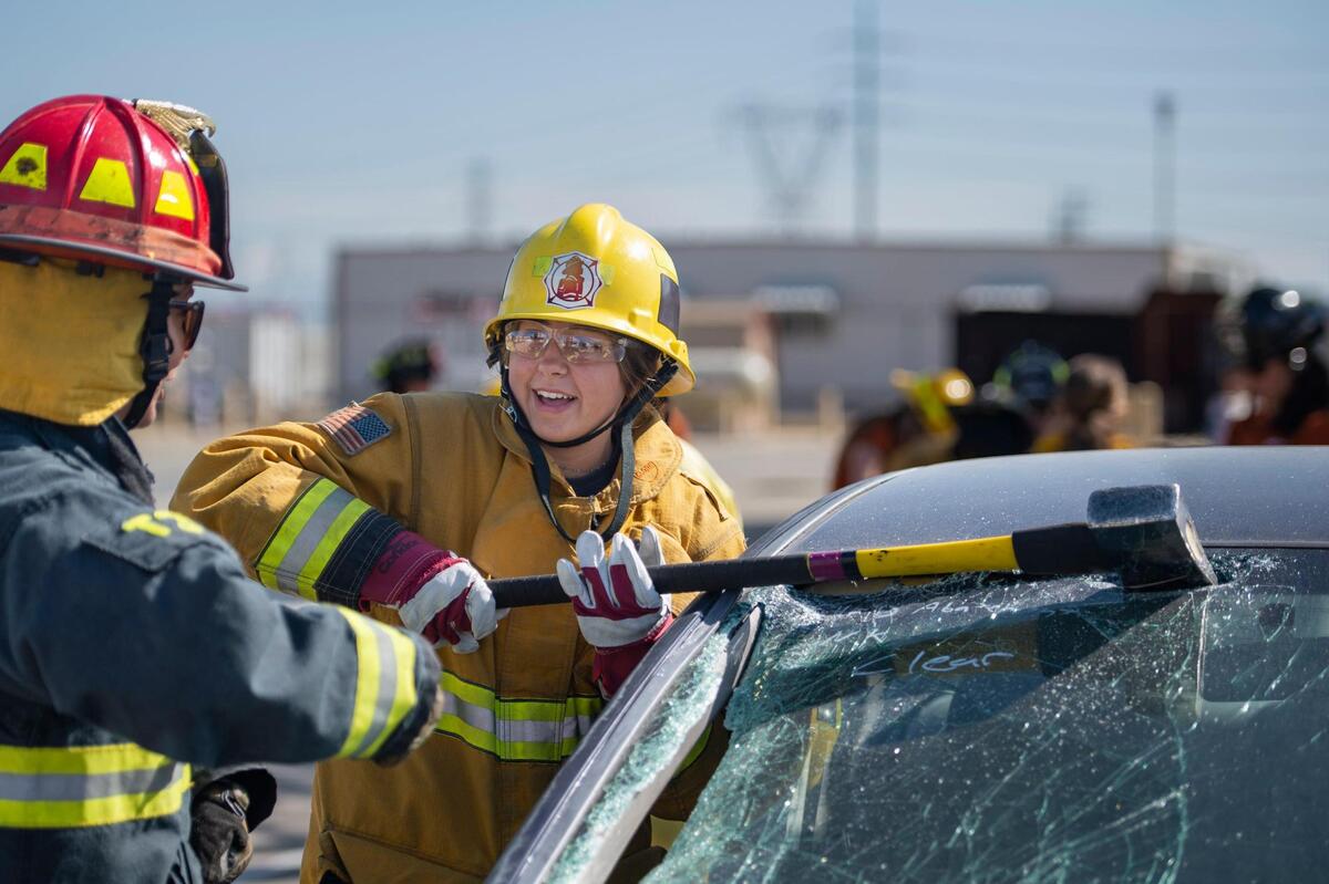 Khloe Parsons, 15, looks to Capt. Asha Whipple of the Woodland Fire Department as she uses an ax to break out a window during the HERo Girls Fire Camp, hosted by the Cosumnes Fire Department, on Sunday.