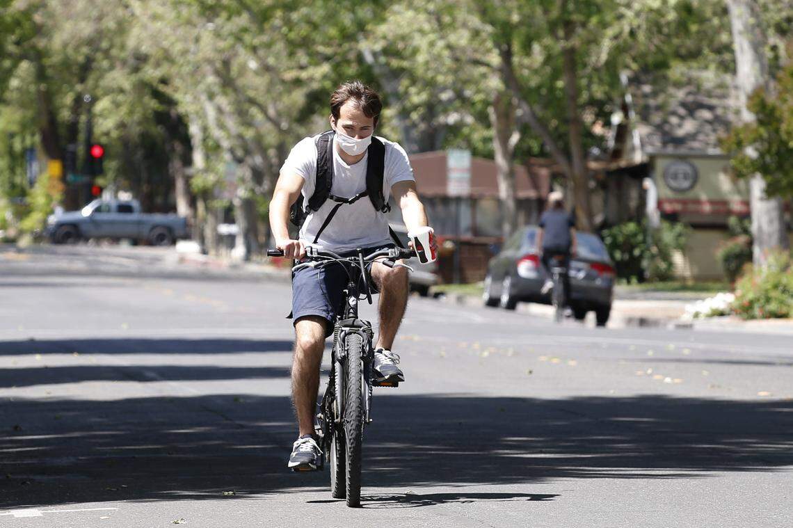 A bicycle rider wears a face mask as he travels through downtown Davis on Monday, April 27, 2020. Yolo County, where Davis is located, now requires people to wear face masks in public. Face coverings are not required for bicycling, running, walking, hiking or at home or alone in a car.