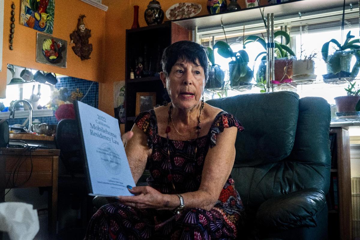 Maria Ruiz holds a book of the state mobile home residency laws as she sits in her home near a window filled with orchids last month. She helped residents living at the Capital Mobile Estates form a chapter of the Golden State Manufactured-Home Owners League and serves as chapter president. Ruiz and others living at the park say the manager is harassing them as their Beverly Hills-based landlord ignores them.