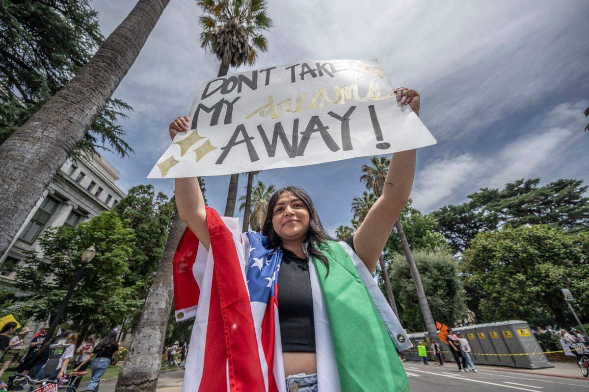 Isabel Amezcua holds a sign that says “don’t take my dreams away” as she carries American and Mexican flags during the “No Kings” protest at the state Capitol on Saturday.