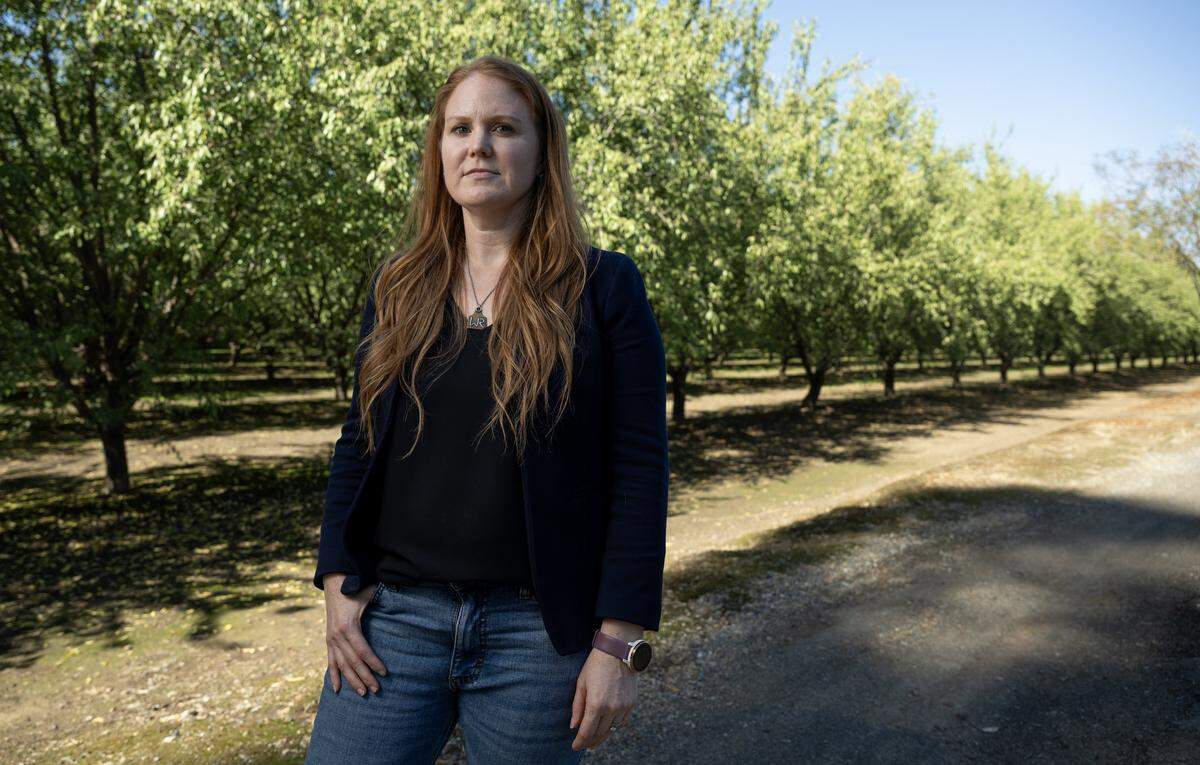 Breanne Vandenberg, executive director of the Merced County Farm Bureau, stands in an almond orchard near Merced on Oct. 21. “Our board has elected to oppose Prop. 50 because it creates issues for rural residents and our community in representation," she said.