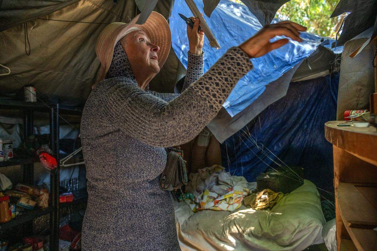 Carol Dutcher, 60, disconnects a light fixture as she scurries to take what she can before her structure is bulldozed in Rio Linda on Monday. “I guess I can’t take my bed,” said Dutcher, who said she had lived at the site for four years. She was able to move a few things and was hoping a friend could come with a pick-up truck before the county loaded it into a dump truck.
