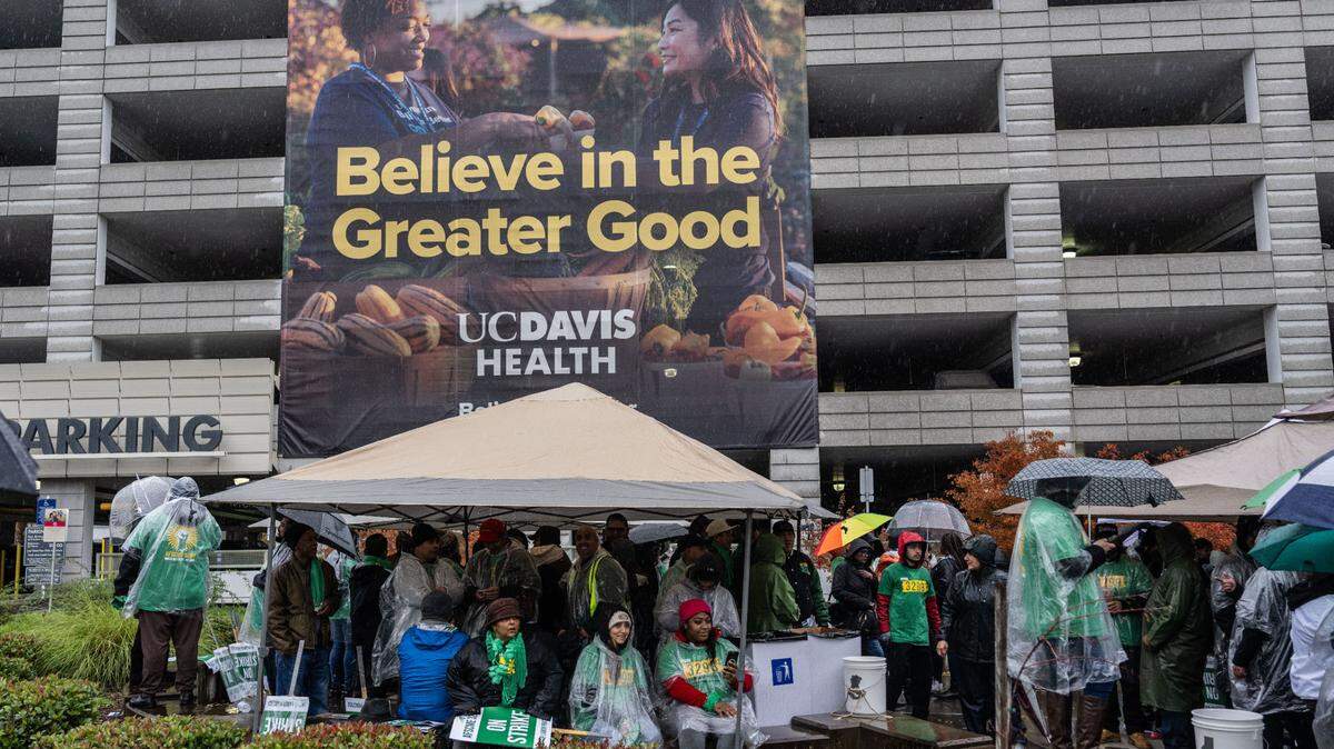 UC Davis Medical Center workers and supporters take cover as rain begins to fall on Wednesday, Nov. 20, 2024 during a state wide strike by AFSCME Local 3299 in the Sacramento campus. The union finally reached a tentative agreement with UC in May 2026.  