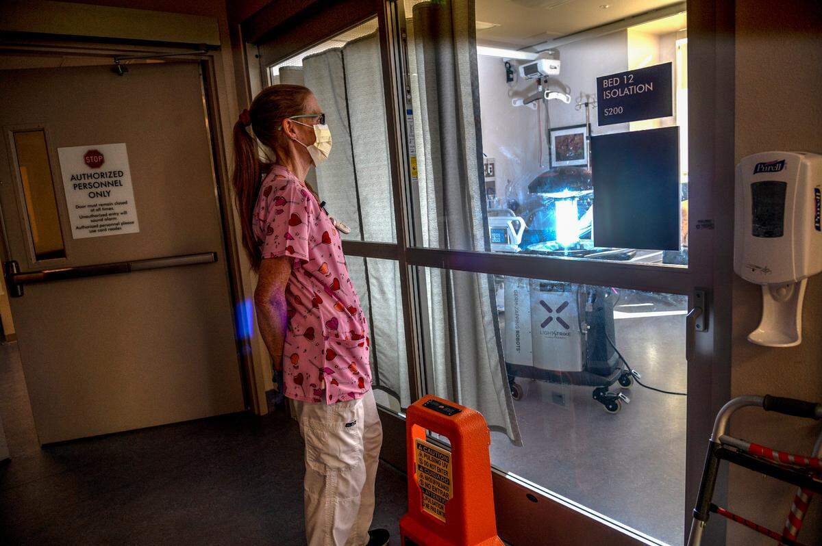 Housekeeper Darci Freeman waits for a robot they call ‘Flash’ to kill germs inside an ICU room for COVID-19 patients at Marshall Medical Center’s hospital in Placerville on Wednesday. The pulsing UV light takes about 15 to 20 minutes to kill the germs in the room. A sign on the door warns people to keep out during the process.