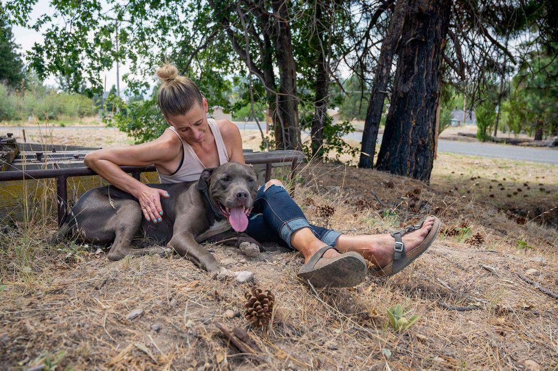 Stephanie Bossen, of Klamath River, kisses her 3-year-old pit bull Biggie while waiting to find out if they can stay at the Weed Community Center for evacuees as the McKinney Fire burns in Klamath National Forest in Siskiyou County on Sunday. Bossen was told dogs were not allowed at the shelter and was referred to the animal shelter in Yreka. Her dog is a rescue from a dog fighting ring and is unable to be around other dogs.
