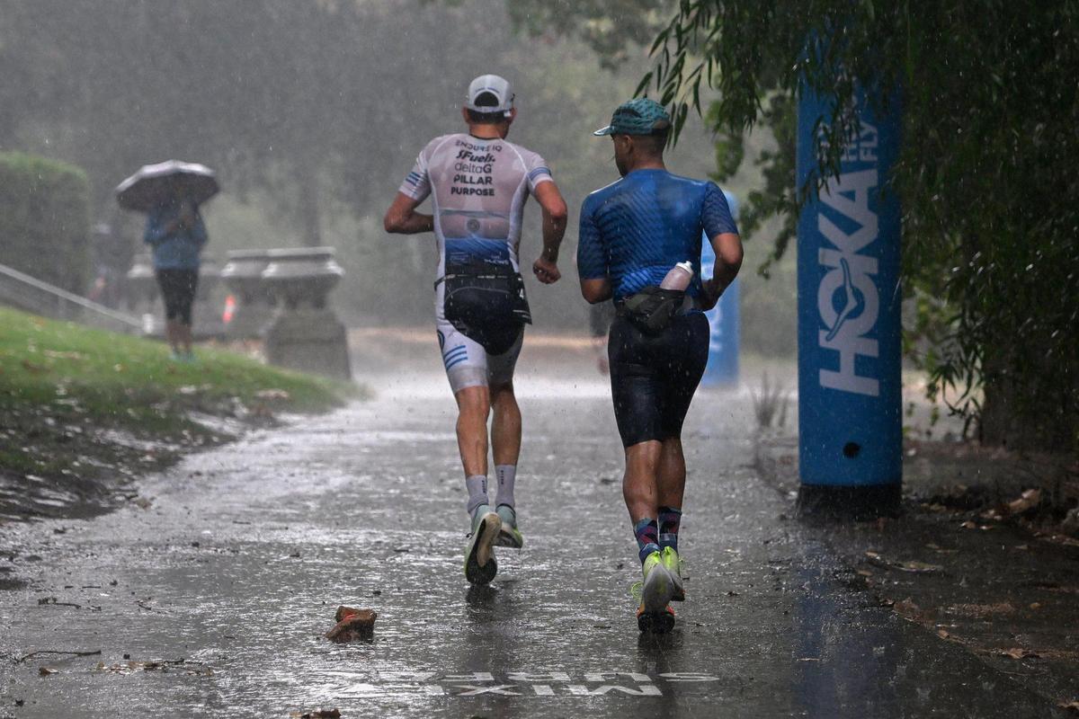 Two participants pass under the Tower Bridge on the running course amid heavy rainfall in West Sacramento during the Ironman California triathlon on Sunday.