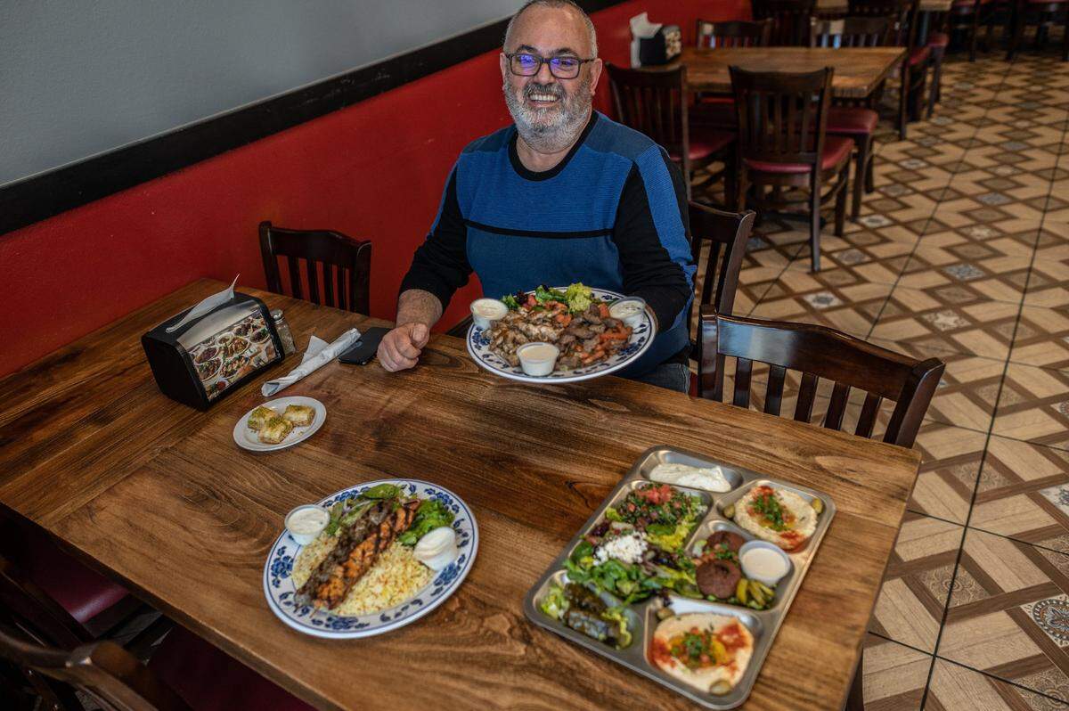 Walid Matar, owner of Wallys Cafe in Rocklin, holds one of his favorite meals to try, Chicken and Beef Shawarma, on Tuesday, Feb. 9, 2021. Also, featured on the table are a veggie sampler and chicken and lab kabobs. All his meals include complimentary homemade lentil soup and baklava for desert. His authentic Lebanese & Mediterranean cuisine is all homemade.
