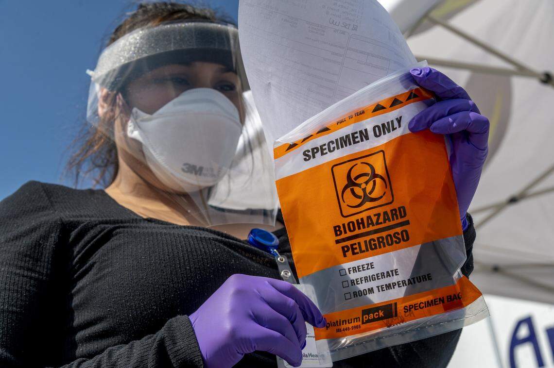 Certified medical assistant Rosa Robles processes a specimen taken for a COVID-19 test. Ampla Health encourages residents to stay home and use its Telehealth phone or video appointments before visiting the drive-through testing site.
